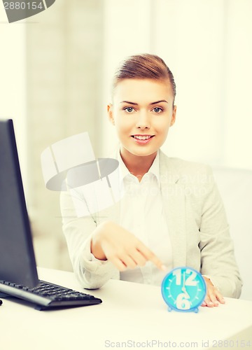 Image of attractive businesswoman pointing at clock