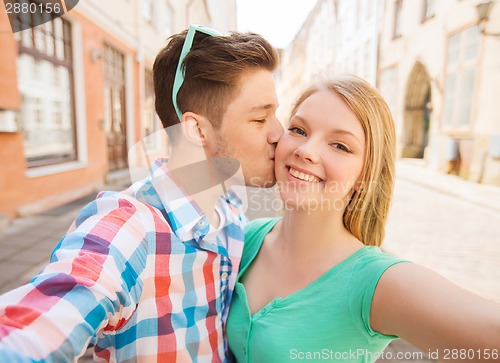 Image of smiling couple with smartphone in city