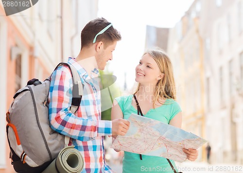 Image of smiling couple with map and backpack in city