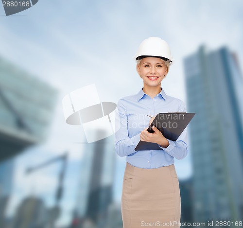 Image of smiling businesswoman in helmet with clipboard