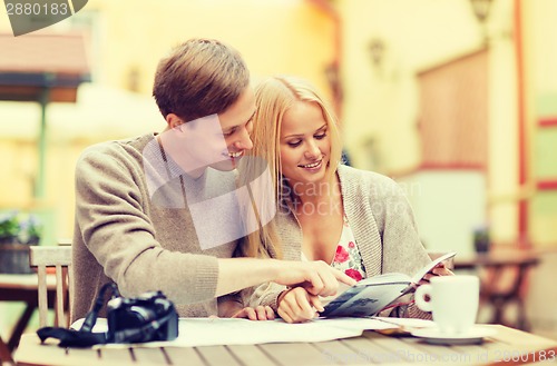 Image of couple with map, camera, city guide and coffee