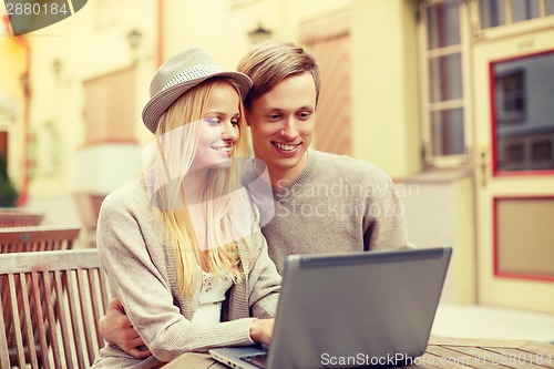 Image of smiling couple with laptop computer in cafe