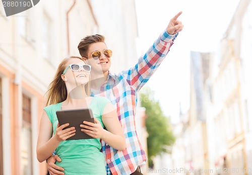 Image of smiling couple with tablet pc in city