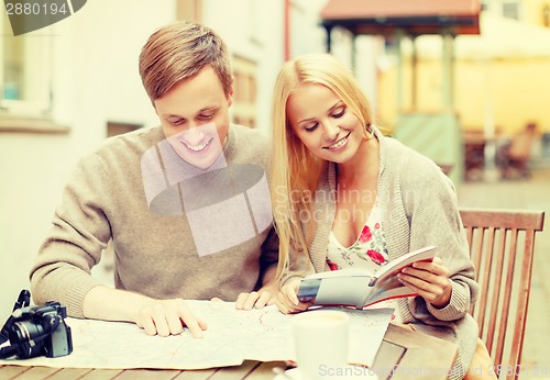 Image of couple with map, camera, city guide and coffee