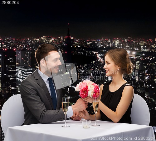 Image of smiling man giving flower bouquet to woman