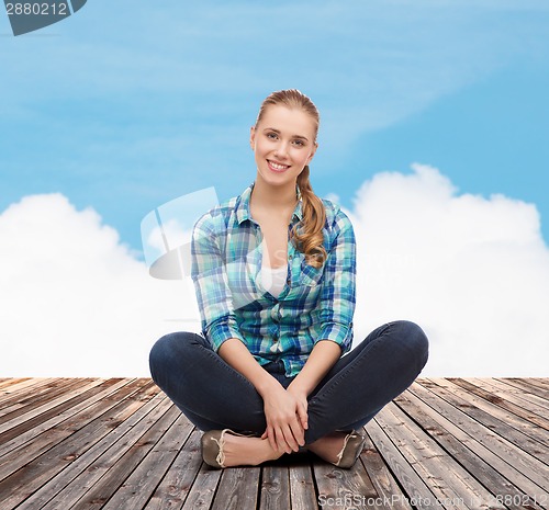 Image of young woman in casual clothes sitting on floor