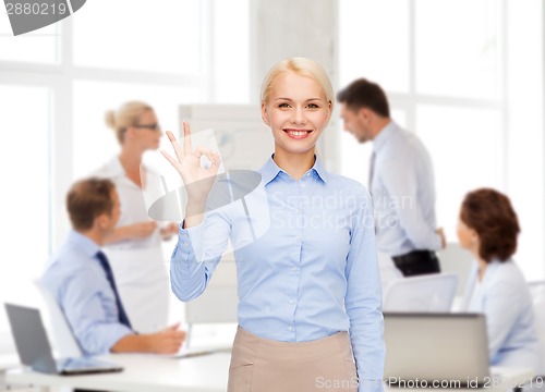 Image of smiling businesswoman showing ok-sign with hand