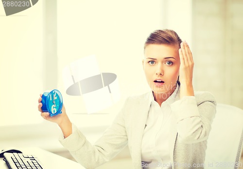 Image of stressed businesswoman holding clock