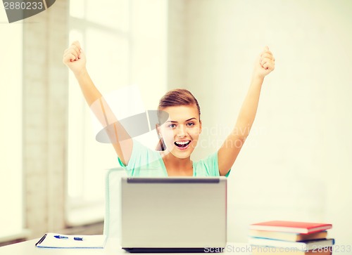 Image of happy student girl with laptop at school