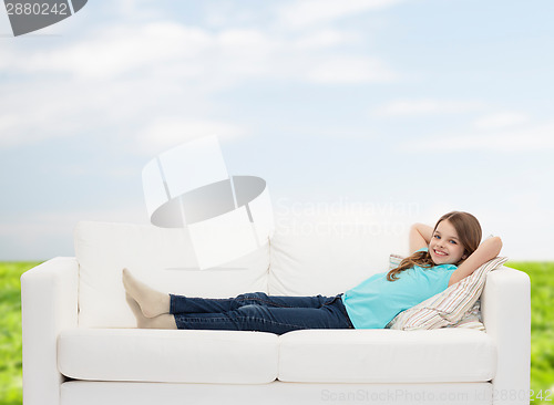 Image of smiling little girl lying on sofa