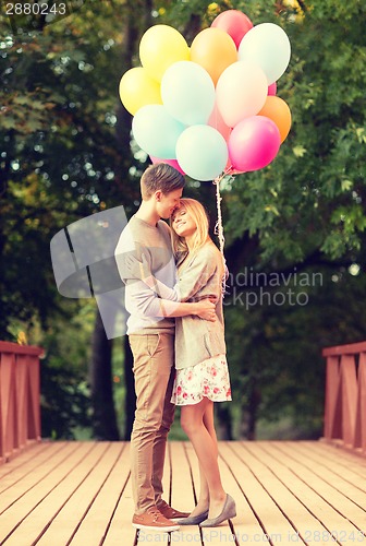 Image of couple with colorful balloons kissing in the park