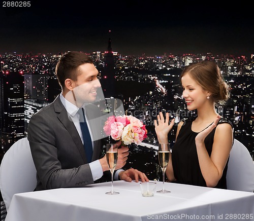 Image of smiling man giving flower bouquet to woman