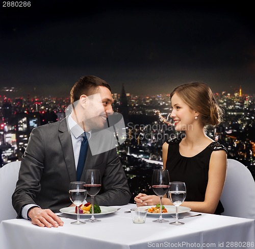 Image of smiling couple eating main course at restaurant