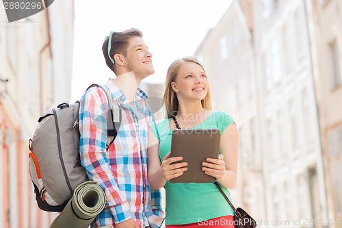 Image of smiling couple with tablet pc and backpack in city