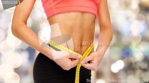 Image of close up of female hands measuring waist