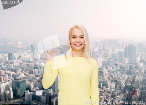 Image of smiling woman pointing her finger up