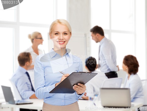 Image of smiling businesswoman with clipboard and pen
