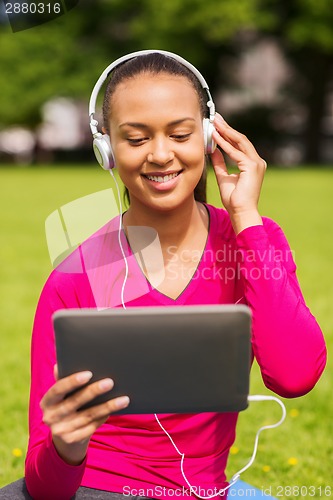 Image of smiling woman with tablet pc outdoors