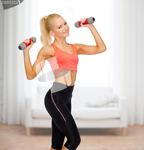 Image of smiling beautiful sporty woman with dumbbells