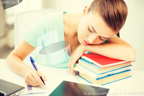 Image of tired student sleeping on stock of books