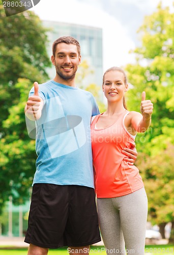 Image of smiling couple showing thumbs up outdoors