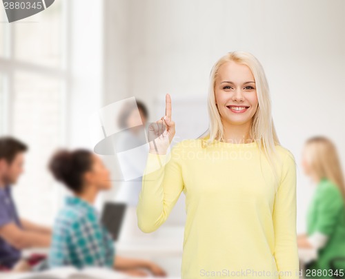 Image of smiling woman pointing her finger up