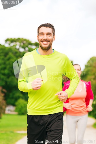 Image of smiling couple running outdoors