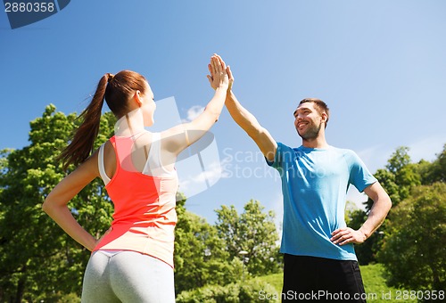 Image of two smiling people making high five outdoors