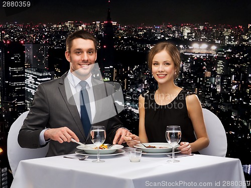 Image of smiling couple eating main course at restaurant