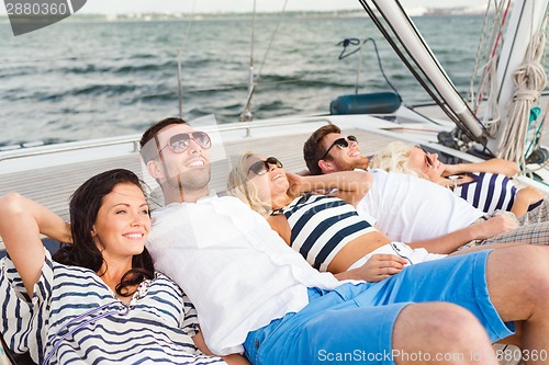 Image of smiling friends lying on yacht deck