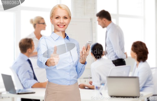 Image of young smiling businesswoman with smartphone