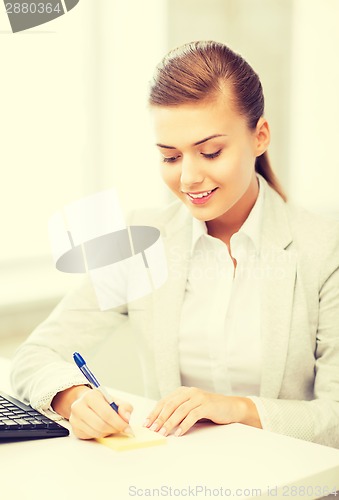 Image of businesswoman writing on sticky note