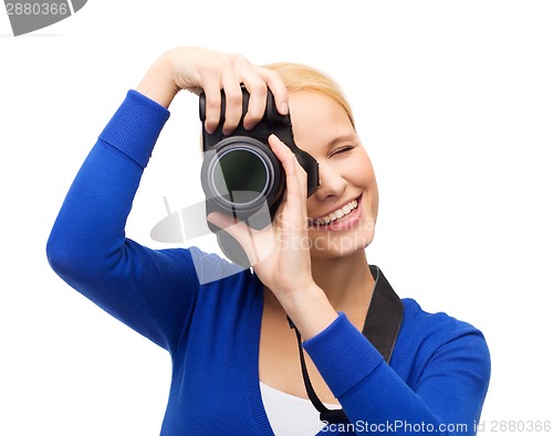 Image of smiling woman taking picture with digital camera