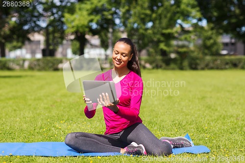 Image of smiling woman with tablet pc outdoors