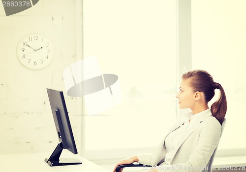 Image of businesswoman looking at wall clock in office