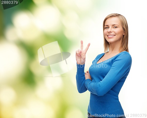 Image of smiling teenage girl showing v-sign with hand