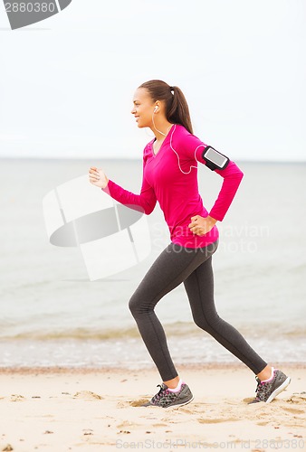 Image of smiling young woman running outdoors