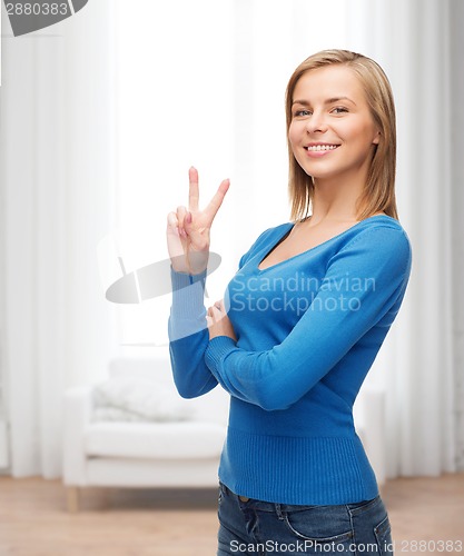 Image of smiling teenage girl showing v-sign with hand