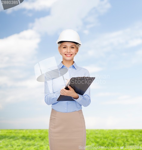 Image of smiling businesswoman in helmet with clipboard