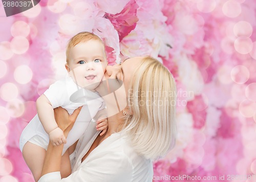 Image of happy mother kissing smiling baby