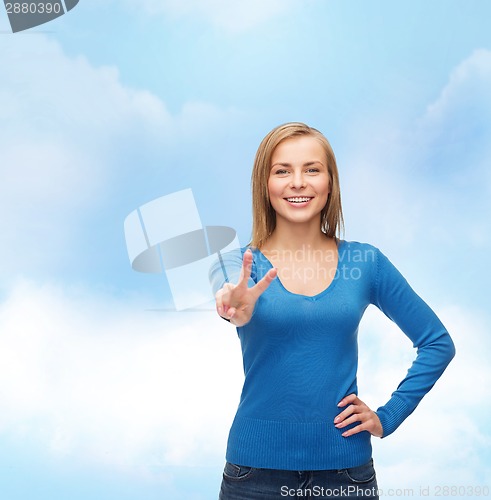 Image of smiling teenage girl showing v-sign with hand