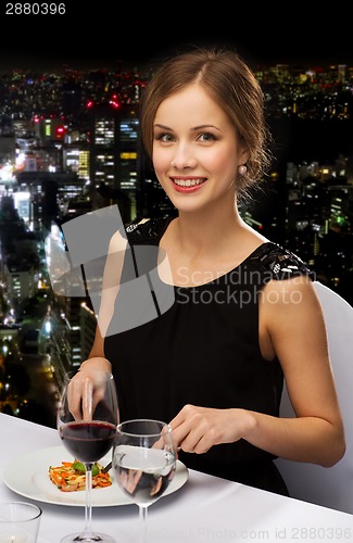 Image of smiling young woman eating main course