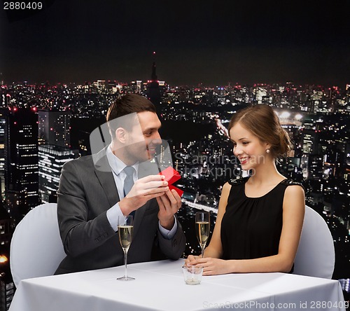 Image of excited young woman looking at boyfriend with box