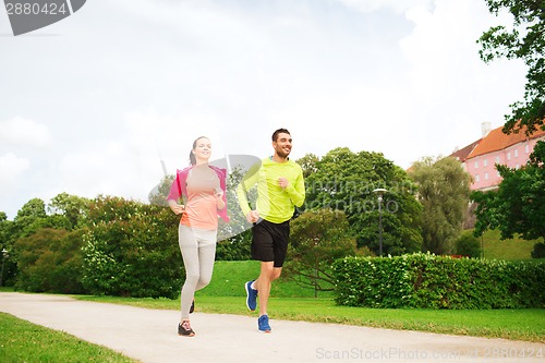 Image of smiling couple running outdoors
