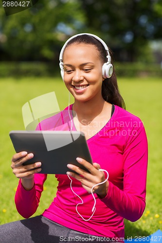 Image of smiling woman with tablet pc outdoors