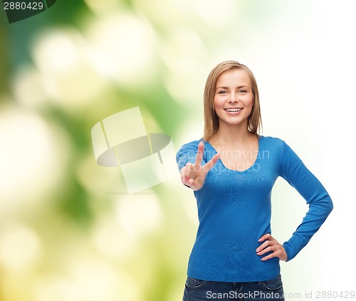 Image of smiling teenage girl showing v-sign with hand