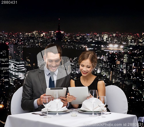 Image of couple with menus on tablet pc at restaurant