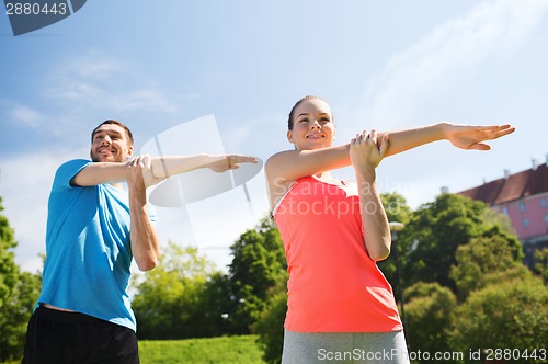 Image of smiling couple stretching outdoors