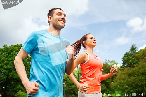 Image of smiling couple running outdoors