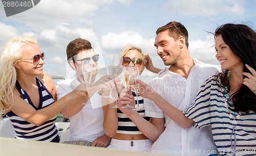 Image of smiling friends with glasses of champagne on yacht